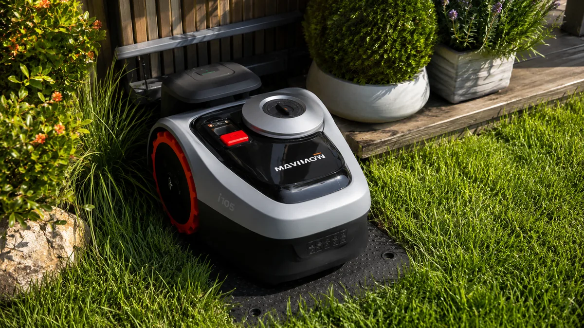 Segway Navimow robotfűnyíró a töltőállomásán egy rendezett teraszos kertben, cserepes növények között